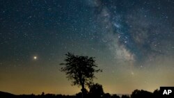 FILE - Mars, left, and the Milky Way are visible in the clear night sky as photographed near Salgotarjan, some 110 kms northeast of Budapest, Hungary, Aug. 03, 2018. 