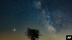 Mars, left, and the Milky Way are visible in the clear night sky as photographed near Salgotarjan, some 110 kms northeast of Budapest, Hungary, Aug. 03, 2018. 