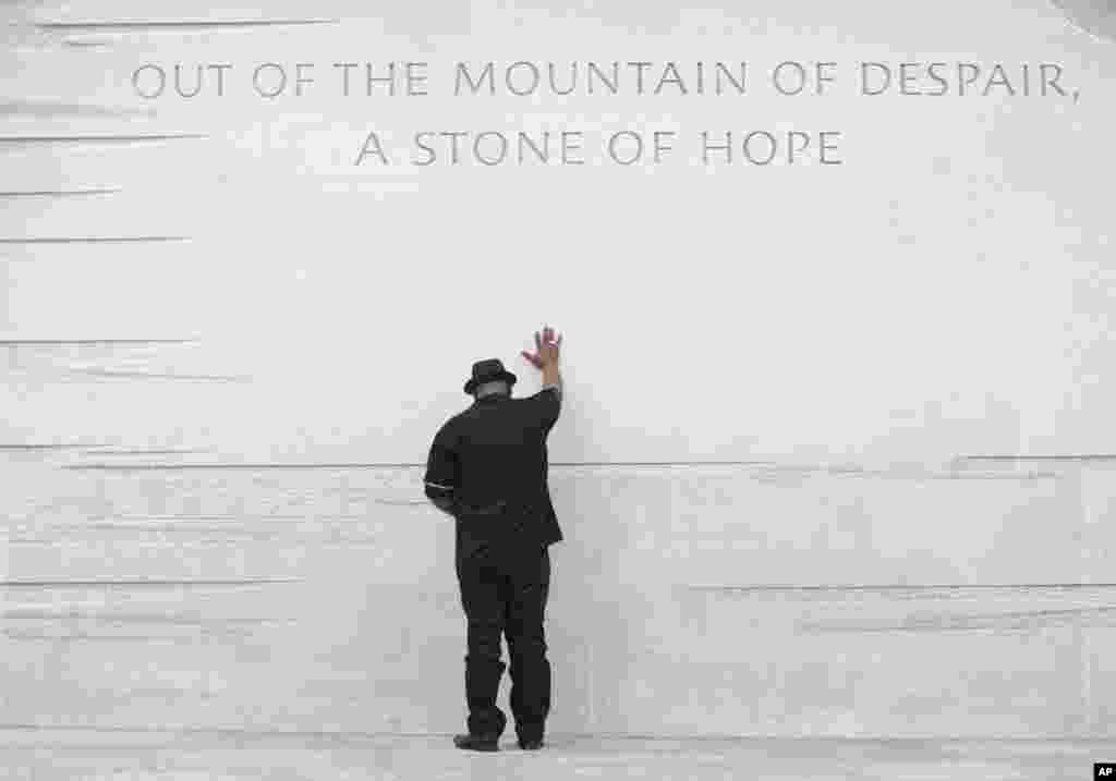 Rev. Bobby Turner or Columbus, Ohio, places his hand on the Martin Luther King Jr. Memorial, Aug. 22, 2013, in Washington.