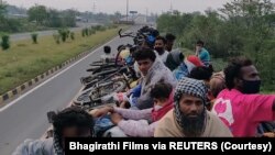 Pekerja migran India yang mudik bersepeda di tengah lockdown akibat Pandemi COVID-19 tahun 2020, menumpang truk dalam perjalanan mereka. (Foto: Bhagirathi Films via REUTERS)