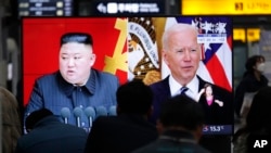 Para penumpang menyaksikan siaran berita yang menampilkan foto Pemimpin Korea Utara Kim Jong Un dan Presiden AS Joe Biden di stasiun kereta Suseo, di Seoul, Korea Selatan, Jumat, 26 Maret 2021. 