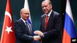 ປະທານາທິບໍດີ ເທີກີ ທ່ານ Recep Tayyip Erdogan, ຂວາ ແລະປະທານາທິບໍດີຣັດເຊຍ ທ່ານ Vladimir Putin ຈັບມືກັນ ທີ່ກອງປະຊຸມ ໃນນະຄອນ Ankara ປະເທດ Turkey ວັນທີ 28 ກັນຍາ, 2017.