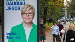 Local resident walk by an election poster showing Lithuania's Homeland Union-Christian Democrats (TS-LKD) party leader Ingrida Simonyte in Vilnius, Lithuania, Oct. 9, 2020. 
