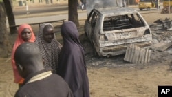 Children stand near the scene of an explosion in a mobile phone market in Potiskum, Nigeria, Jan. 12, 2015. 