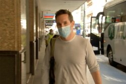 FILE - Australian Broadcasting Corp. journalist Bill Birtles walks into a hotel for quarantine in Sydney, Australia, Sept. 8, 2020.