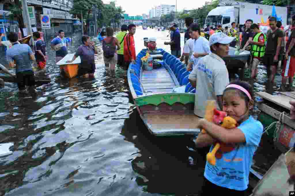 An evacuee clutches a stuffed animal after arriving at the Thon Buri bridge Sunday evening. Her house was flooded for days when it rose suddenly to one meter two days ago, Bangkok, October 31, 2011. (VOA)