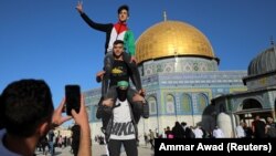 Pemuda Palestina berpose dengan Kubah Batu terlihat di latar belakang, saat shalat Idulfitri di kompleks Masjid al-Aqsa di Kota Tua Yerusalem, di tengah pertempuran Israel-Gaza, 13 Mei 2021. (Photo: REUTERS/Ammar Awad)