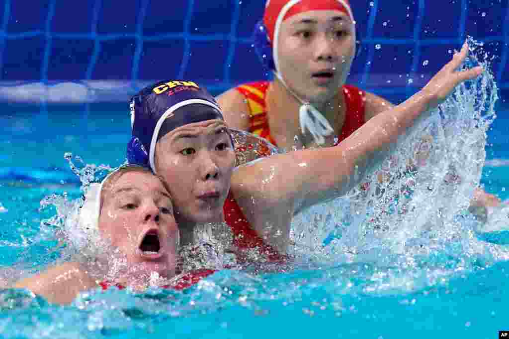 Hungary&#39;s Aniko Gyongyossy, left, and China&#39;s Wang Huan battle for position in front of China&#39;s goalkeeper Shen Yineng, right, during a preliminary round women&#39;s water polo match at the 2020 Summer Olympics in Tokyo, Japan.