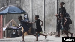 A woman and three children flee their home from gang violence in Port-au-Prince, Haiti, on Oct. 20, 2024.