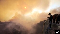 Aaron Kaboud sprays water off the deck of his family's home that was spared by a wildfire that hit the Bel Air district of Los Angeles, Dec. 6, 2017. 