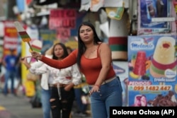 A vendor waves a popsicle-shaped sign to attract prospective customers in Salcedo, Ecuador, Thursday, Nov. 28, 2024. (AP Photo/Dolores Ochoa)