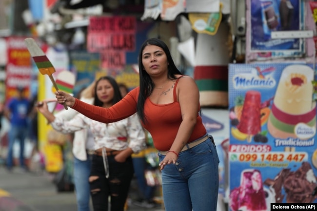 A vendor waves a popsicle-shaped sign to attract prospective customers in Salcedo, Ecuador, Thursday, Nov. 28, 2024. (AP Photo/Dolores Ochoa)