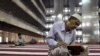 FILE - A man reads the Koran at Istiqlal mosque in Jakarta, July 24, 2012. 