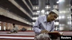 FILE - A man reads the Koran at Istiqlal mosque in Jakarta, July 24, 2012. 