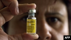 FILE - A nurse displays a vial of vaccine in Brasilia, Brazil. The World Health Organization is urging travelers to Angola to get a yellow fever vaccination. 