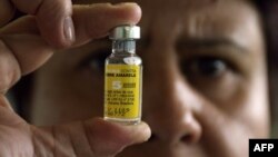 FILE - A nurse displays a vial of yellow fever vaccine in Brasilia, Brazil. So far, over 15 million doses of the Yellow Fever vaccine have been delivered to Angola and the neighboring Democratic Republic of Congo.