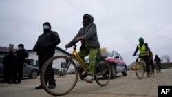 Vietnamese workers who are helping to build the first Chinese car tire factory in Europe, cycle in front of security officials near the northern Serbian city of Zrenjanin, 50 kilometers north of Belgrade, on November 18, 2021.