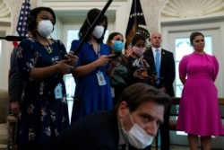 Journalists take notes as President Donald Trump speaks before signing a coronavirus aid package to direct funds to small businesses, hospitals, and testing, in the Oval Office of the White House, April 24, 2020, in Washington.