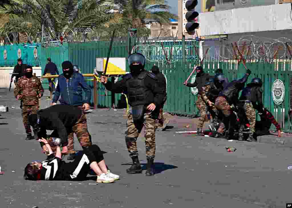 A riot policeman pins down a female anti-government protester to search her while security forces disperse demonstrators during clashes in Baghdad, Iraq.