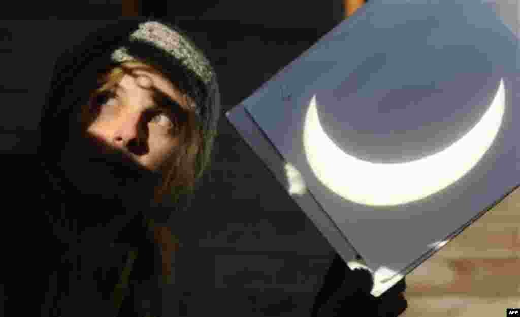 An unidentified employee of the Stefanik Observatory in Prague uses a projection shield to show the partial solar eclipse visible in the Czech capital during the morning on Tuesday, Jan. 4, 2011. The partial Sun eclipse started over the Czech Republic at