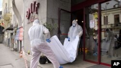 Forensic workers carry the body of Gholamreza Mansouri from a hotel in downtown Bucharest, Romania, June 19, 2020. 