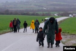 FILE - Migrants walk along a road from the village of Chamilo to the migrant camp at the village of Idomeni, near the Greek-Macedonian border, Greece, March 15, 2016.