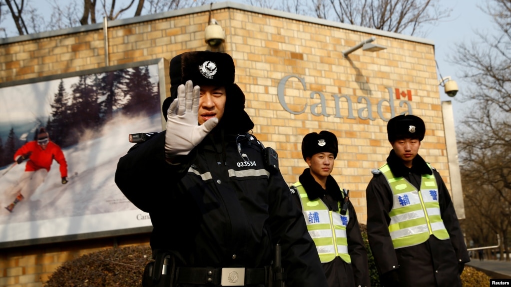 在加拿大驻北京大使馆外的一名中国警察向摄影记者打出禁止的手势。（2018年12月20日）(photo:VOA)