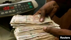 FILE - Cashier counts Kenya shillings in Nairobi. A new report says more than 40 percent of Kenyans cannot afford to retire and must continue working.