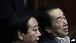 Japanese Finance Minister Yoshihiko Noda (L) talks with Prime Minister Naoto Kan before a regular session at the lower house of parliament in Tokyo, June 9, 2011