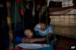 Rohingya Muslim refugee Noor Kadir, 24, from the Myanmar village of Gu Dar Pyin, plays with his son inside the family makeshift shelter in Balukhali refugee camp, Bangladesh, Jan. 21, 2018.