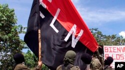 ARCHIVO - Miembros del Ejército de Liberación Nacional (ELN) levantan su bandera en San Francisco, una región montañosa en el norte de Colombia, en octubre de 1998.