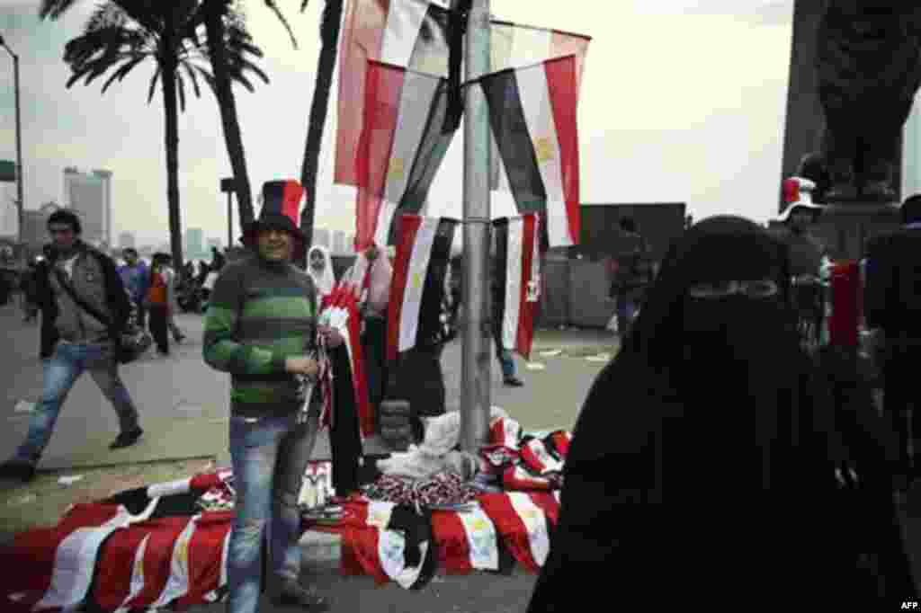 An Egyptian man sells flags and hats outside Tahrir Square in Cairo, Egypt, Wednesday, Feb. 9, 2011. Protesters appear to have settled in for a long standoff, turning Tahrir Square into a makeshift village with tens of thousands coming every day, with som