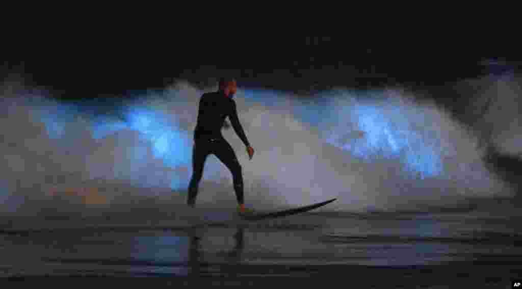 A surfer rides a wave as bioluminescent plankton lights up the surf around him during the coronavirus outbreak, April 30, 2020, in Newport Beach, Calif. 