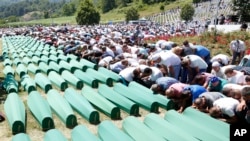 FILE - A July 11, 2016 photo of Bosnian people praying in front of coffins during a funeral ceremony for the 127 victims at the Potocari memorial complex near Srebrenica, 150 kilometers northeast of Sarajevo, Bosnia and Herzegovina.