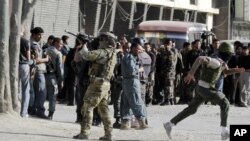 Un soldado de la OTAN defiende a los civiles que se protegen de los disparos en Kabul, durante el ataque de este domingo.