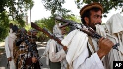 FILE - In this Sunday, July 31, 2011 file photo, Taliban fighters hold their heavy and light weapons before surrendering them to Afghan authorities in Jalalabad, east of Kabul, Afghanistan. 