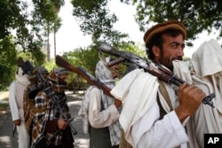 FILE - Taliban fighters hold their heavy and light weapons before surrendering them to Afghan authorities in Jalalabad, east of Kabul, Afghanistan.