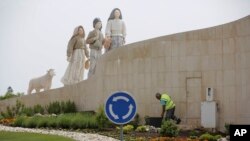 A gardener tends to flowers on a roundabout underneath a statue of the three shepherd children who say they saw visions of the Virgin Mary 100 years ago, in Fatima, Portugal, May 4, 2017. 