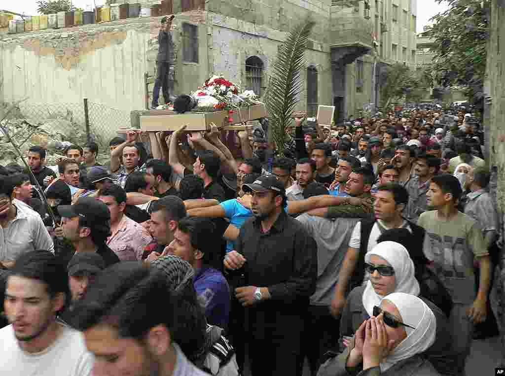 Anti-Syrian regime mourners shout slogans and carry the body of activist Nour al-Zahraa. (AP)