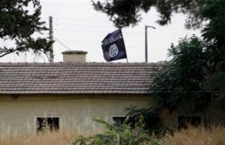 FILE - An Islamic State flag flies over a building in Syria's Jarablus as seen from the Turkish town of Karkamis, Turkey, Aug. 1, 2015.