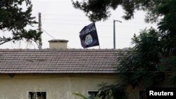 An Islamic State flag flies over a building in Syria's Jarablus as seen from the Turkish town of Karkamis, Turkey, Aug. 1, 2015.