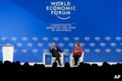 Klaus Schwab, founder and Executive Chairman of the World Economic Forum, talks with German Chancellor Angela Merkel after she addressed the annual meeting of the World Economic Forum in Davos, Switzerland, Jan. 23, 2019.