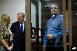 FILE - Paul Whelan, a former US Marine (R), arrested in Moscow at the end of last year, looks through a cage's glass as his lawyers talk to each other in a court room in Moscow, Russia, Jan. 22, 2019.