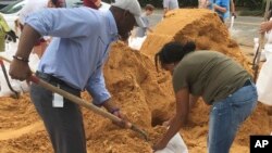 Tallahassee Mayor and Democratic gubernatorial candidate, Andrew Gillum, left, helps Eboni Sipling fill up sandbags in Tallahassee, Florida, Oct. 8, 2018. 