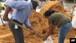 Tallahassee Mayor and Democratic gubernatorial candidate, Andrew Gillum, left, helps Eboni Sipling fill up sandbags in Tallahassee, Florida, Oct. 8, 2018. 