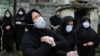 Relatives of a victim who died from the new coronavirus mourn at the gate of a cemetery, in the outskirts of the city of Babol, in north of Iran, April 30, 2020.