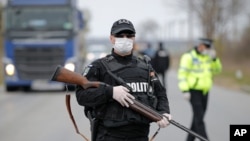 FILE - Police officers check motorists on a road access point to Tandarei, eastern Romania, April 4, 2020, after authorities imposed a severe quarantine status on the city.