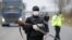 FILE - Police officers check motorists on a road access point to Tandarei, eastern Romania, April 4, 2020, after authorities imposed a severe quarantine status on the city.
