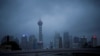 FILE - People walk with umbrellas on a bridge amid rains and winds brought by Typhoon Muifa, in Shanghai, Sept. 14, 2022. 