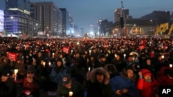 Protesters hold candles during a rally calling for South Korean President Park Geun-hye to step down in Seoul, South Korea, Dec. 24, 2016. The letters read "Arrest, Park Geun-hye."